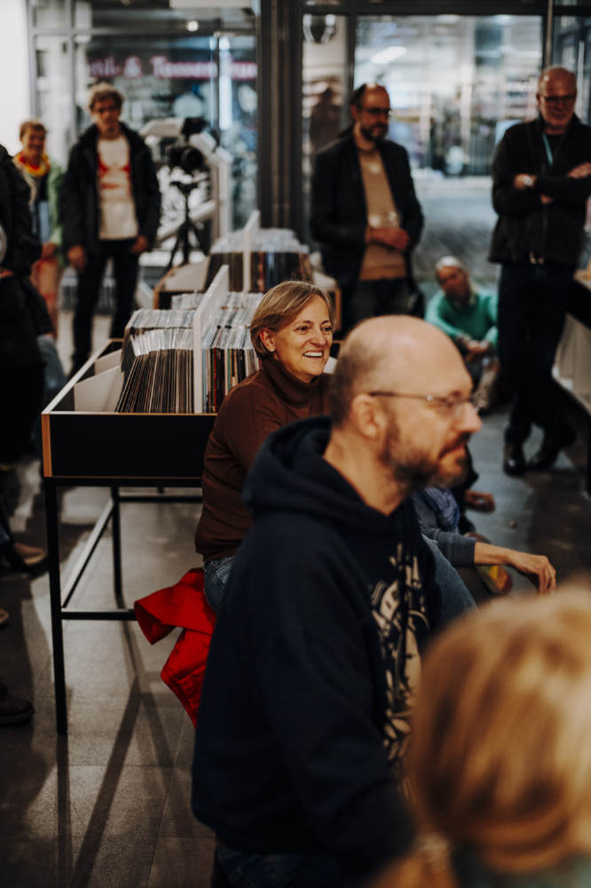 Menschen sitzen in den Räumen des Plattenladens und hören Musik