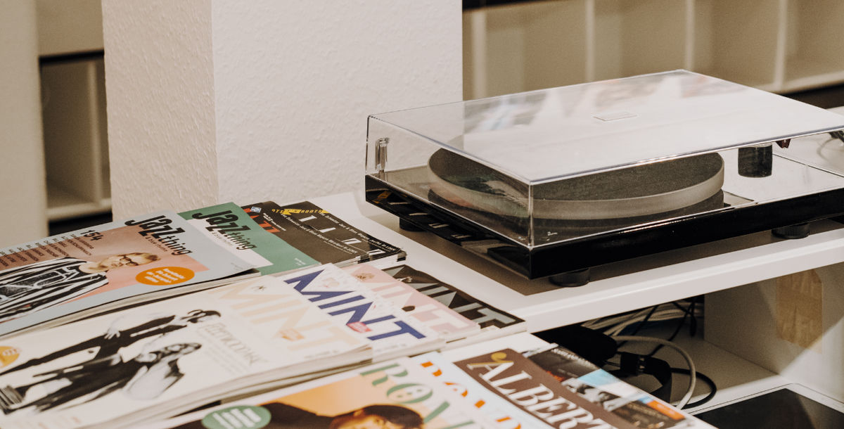 Bild zeigt ein Plattenspieler mit Musikzeitschriften auf einem Tresen